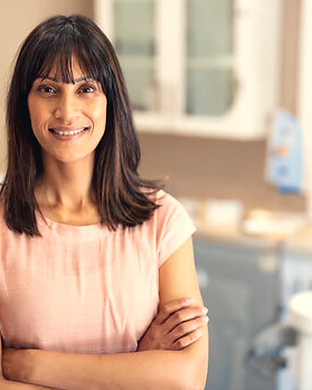 A business owner in her workplace, arms folded, smiling.